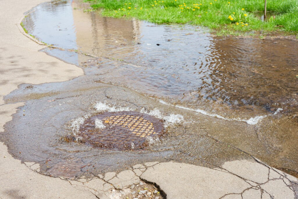 Vandstrømmer ud af kloakdæksel, gennembrud i kloaksystemet, uheld med vandforsyningen